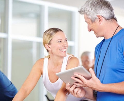 Trainer berät Frau im Fitnessstudio